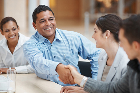 Man smiling and shaking hands with another