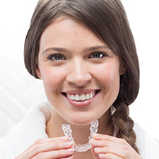 Smiling woman holding Invisalign device